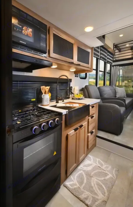Modern RV rental interior featuring a well-appointed kitchen with stove, oven, microwave, and a comfortable living area beyond.. Forest River Timberwolf 16ML 2024