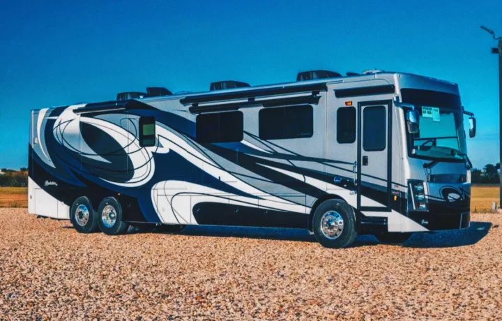 Luxurious motorhome with a distinctive blue, gray, and white swirl design, parked on gravel under a blue sky; an ideal RV rental.. Forest River Berkshire 2023