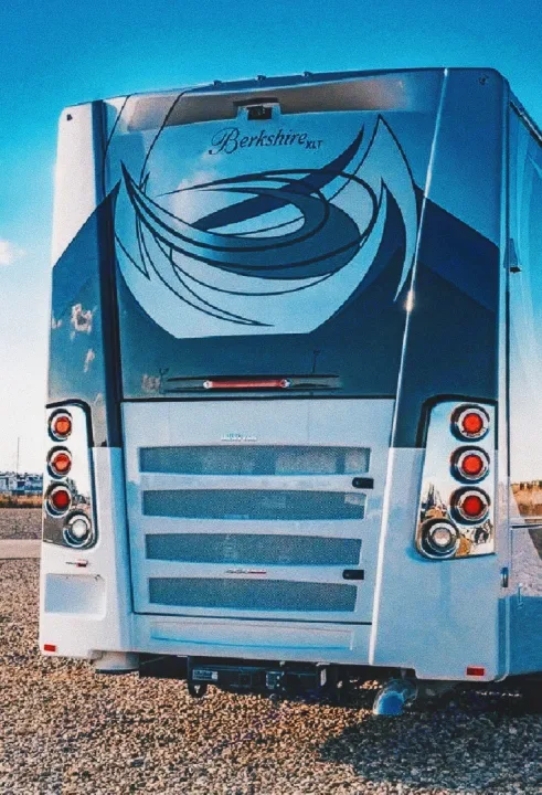 Rear view of a Berkshire XLT RV, perfect for your next rv rental adventure. Parked on gravel under blue sky.. Forest River Berkshire 2023