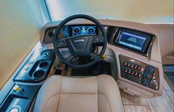 Inside a modern RV rental: the ergonomic driver's cockpit, featuring a digital dashboard, large display, and plush seating.. Forest River Berkshire 2023