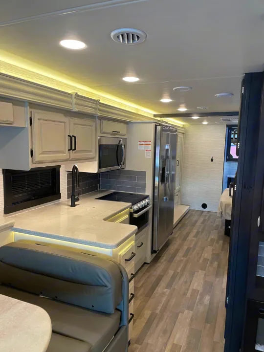 This RV rental boasts a contemporary kitchen, dining area, and hallway leading to a bedroom, perfect for travel.. Entegra Coach Vision XL 2024