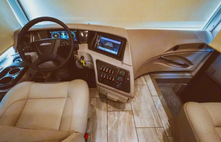Explore this bright RV rental cockpit: cream leather seats, sleek dashboard with digital displays, and modern controls.. Forest River Berkshire 2023