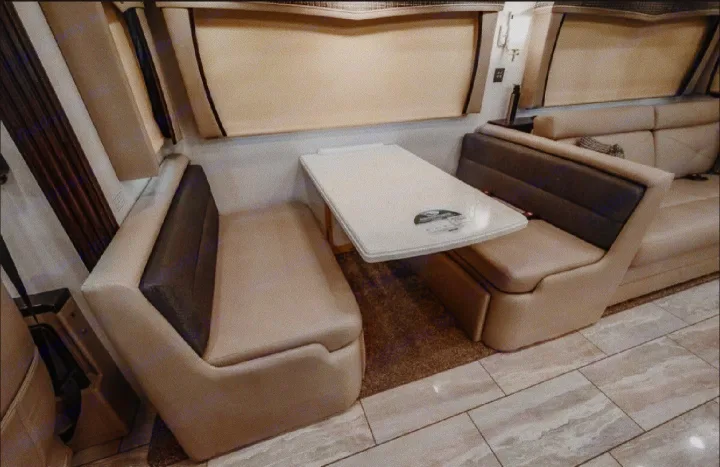 Spacious RV rental dinette featuring a white table & opposing cushioned bench seating with shades.. Forest River Berkshire 2023