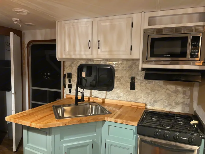 Modern RV rental kitchen with new butcher block counters, light blue cabinets, and stainless appliances. Perfect for travel!. Gulf Stream Conquest 2016