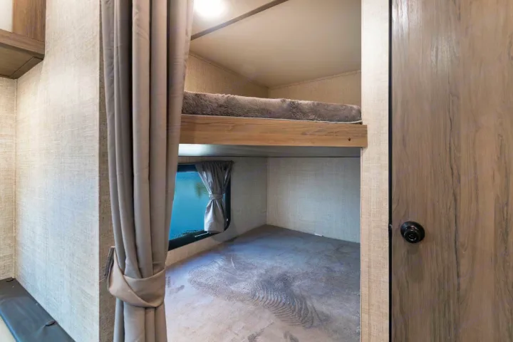 Cozy RV rental bunk beds: The top bunk features a fuzzy pad, while the lower bunk offers a window with a serene water view.. Gulf Stream Friendship 2022