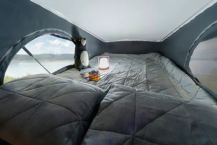 Enjoy ultimate comfort in this RV rental's pop-top bed. Features cozy bedding, a lamp, and stunning lake views for your camping adventures.. Winnebago Solis PX 2025