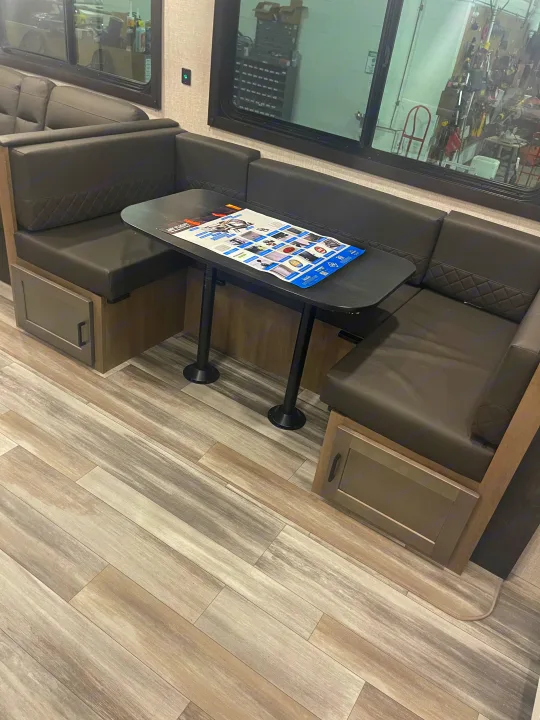 Cozy RV rental dinette featuring dark upholstered seating, a functional table, and light wood-look flooring, ideal for travel.. Jayco JayFlight 2024