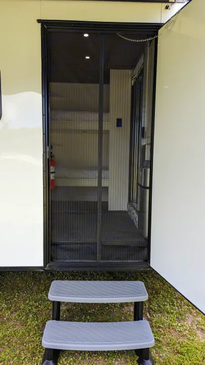 Experience an RV rental! View of open entry with pleated screen door, visible bunk beds, and sturdy outdoor steps.. Diamond Cargo 16x8.5 2023