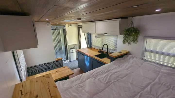 Explore this RV rental's functional interior: cozy bed, full kitchenette, and compact living space with wooden accents.. Diamond Cargo 16x8.5 2023