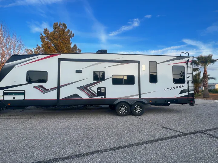 A white Stryker recreational vehicle with bold black/red graphics, ideal for an RV rental, parked on asphalt.. Cruiser Rv Corp Stryker 2021