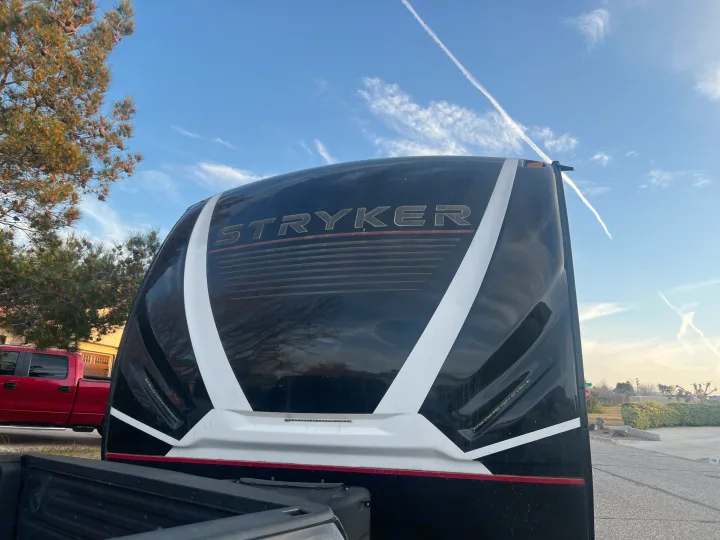 Stryker RV rental: Rear of this black & white toy hauler reflects trees & blue sky. Truck bed in foreground.. Cruiser Rv Corp Stryker 2021
