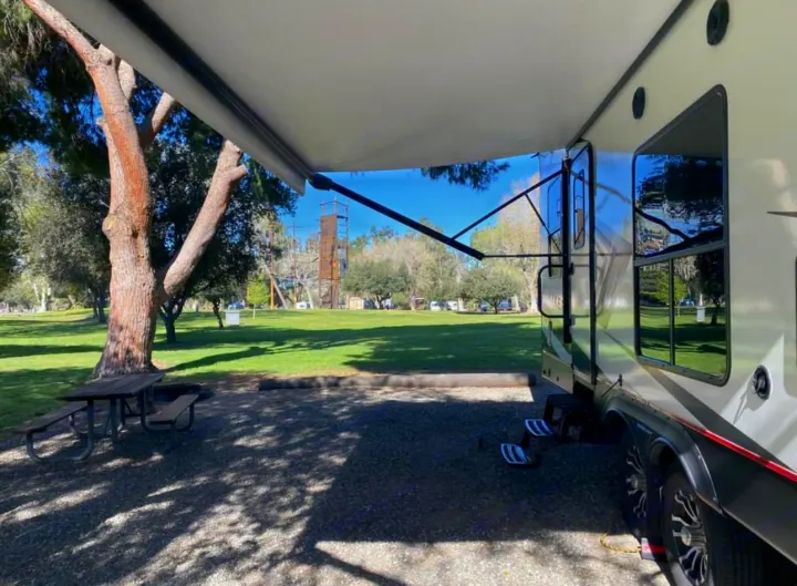 Enjoying an RV rental at a sunny campground campsite with an extended awning, picnic table, and grassy area.. Cruiser Rv Corp Stryker 2021
