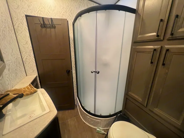 Compact RV rental bathroom with a curved shower, sink, toilet, and storage cabinets, offering comfort on the go.. Cruiser Rv Corp Stryker 2021