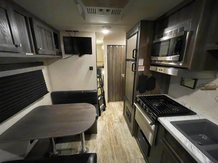 Inside a modern rv rental: full kitchen, dining booth, wall-mounted TV, and bunk beds, offering a complete living space.. Highland Ridge RV Open Range 2019