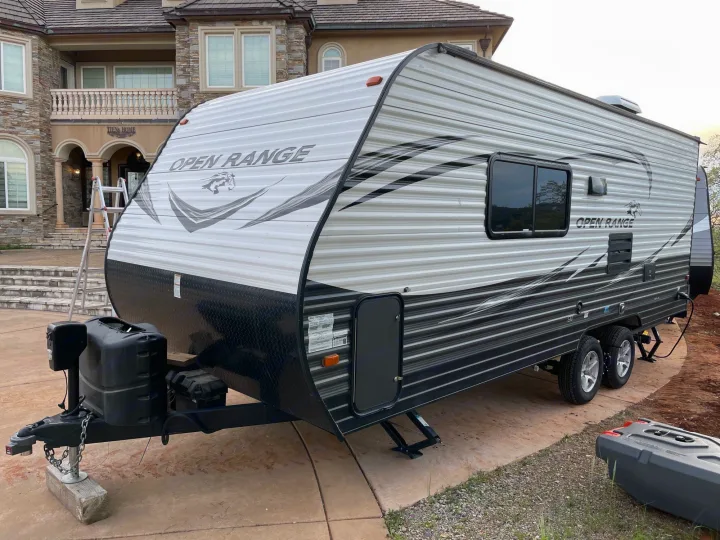 Open Range travel trailer RV rental, with black and white exterior, parked on a concrete driveway.. Highland Ridge RV Open Range 2019