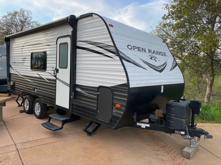 An Open Range travel trailer parked on a patio, ready for RV rental adventures. Ideal for your next outdoor getaway.. Highland Ridge RV Open Range 2019