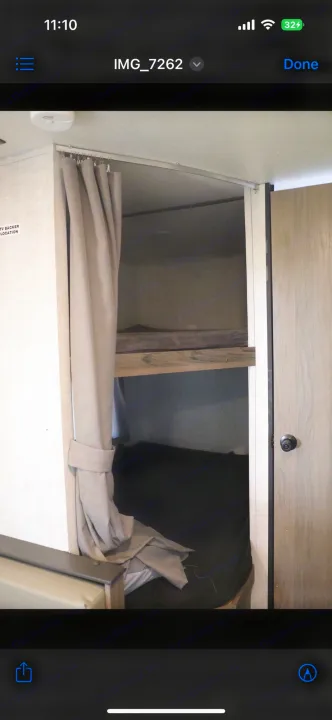 RV rental: Interior view of bunk beds with a tied-back curtain, showing mattresses in a cozy space.. Gulf Stream Enlighten 2022