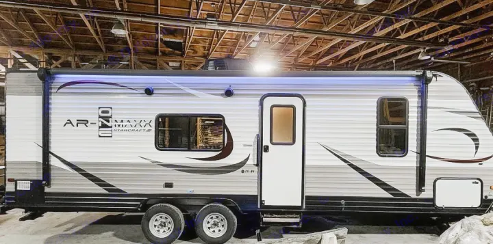 Grey and white Starcraft AR-ONE MAXX travel trailer, with illuminated awning, parked indoors. Great for an rv rental.. Starcraft AR-One Maxx 2017