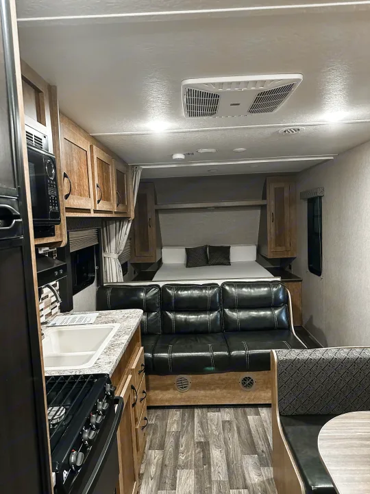 Bright, modern rv rental interior showing a kitchen, black sofa, dinette, and a comfortable bed area.. Starcraft AR-One Maxx 2017