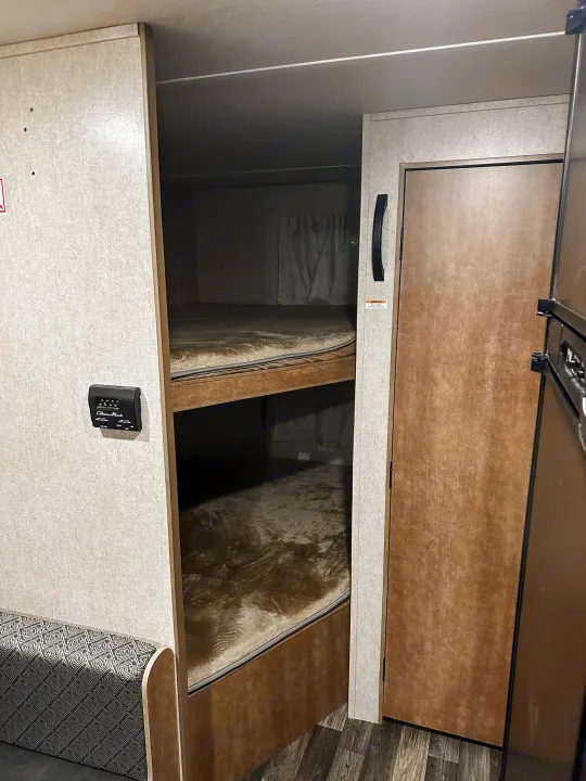 Cozy RV rental interior featuring bunk beds, a thermostat, and part of a fridge, perfect for camping travel.. Starcraft AR-One Maxx 2017