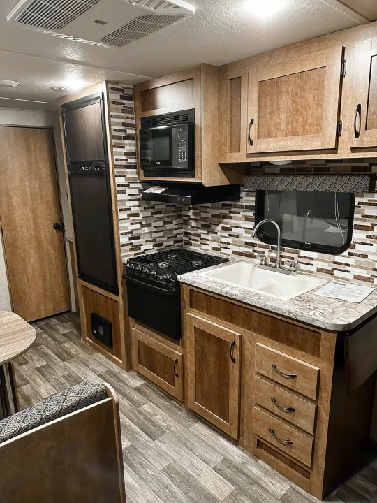 Inside an RV rental, a well-equipped kitchen features wood cabinets, stove, microwave, fridge, sink, and dining area.. Starcraft AR-One Maxx 2017