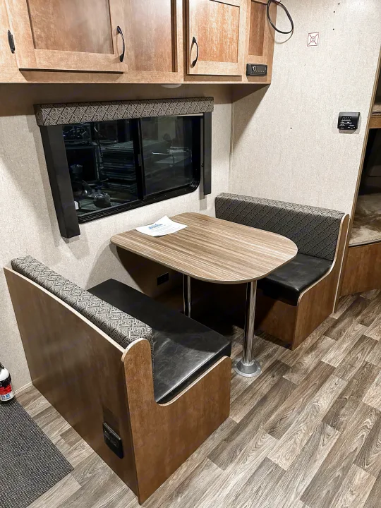 Cozy RV rental dinette with wood-look table, upholstered benches, and overhead cabinets, perfect for meals on the go.. Starcraft AR-One Maxx 2017