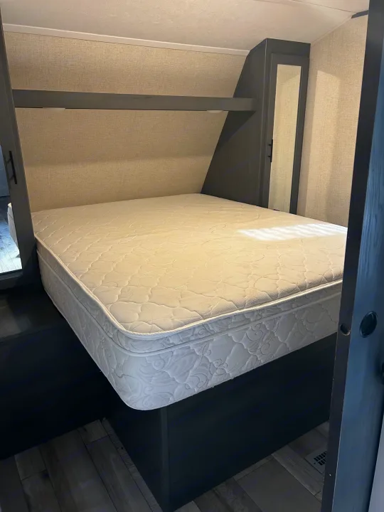 Spacious RV rental bedroom with a comfortable mattress, built-in storage, and modern dark wood accents.. Aspen Trail 3280BHS 2022