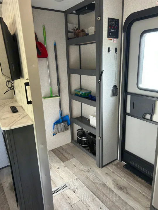 RV rental interior with functional storage shelves, a convenience control panel, main entry door, and cleaning essentials.. Aspen Trail 3280BHS 2022