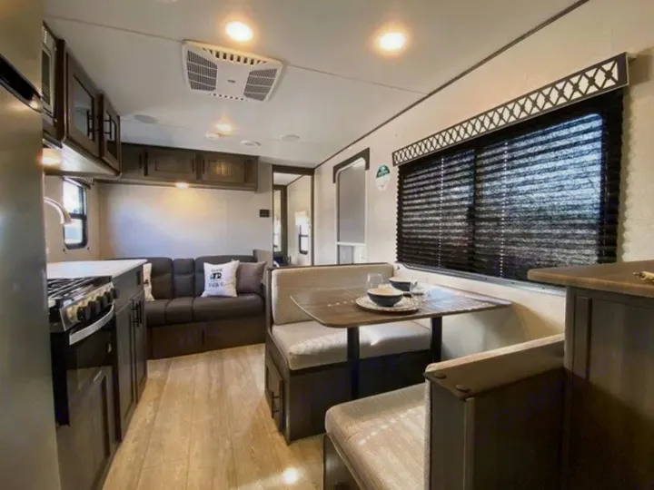 Modern RV rental interior showing a full kitchen, comfy dining booth, and living room sofa.. Shasta Oasis 2021