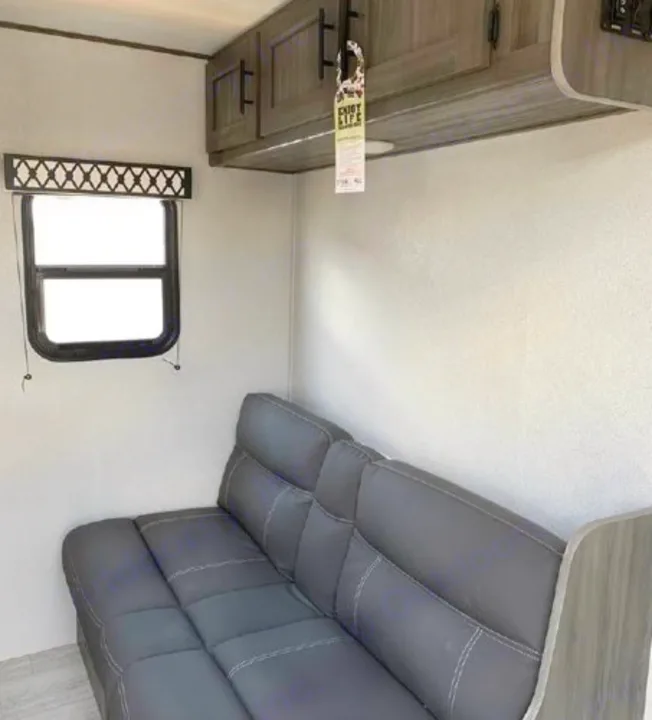 Comfortable gray sofa and overhead cabinets inside an RV rental. Perfect for travel and relaxation.. Shasta Oasis 2021