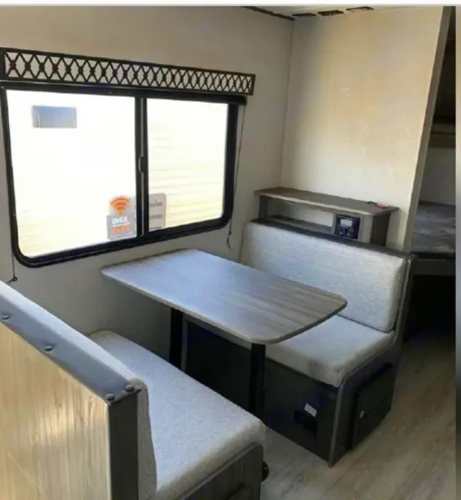 An RV rental's dinette area featuring comfortable upholstered benches, a table, and a large window for scenic views.. Shasta Oasis 2021