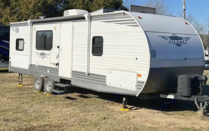 White and gray Shasta travel trailer, ideal for your next RV rental. Parked outdoors with stabilizers down.. Shasta Oasis 2021