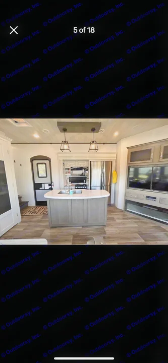 Spacious RV rental interior featuring a modern kitchen island, full-size fridge, and living area with TV & fireplace.. Keystone RV Cougar 2021