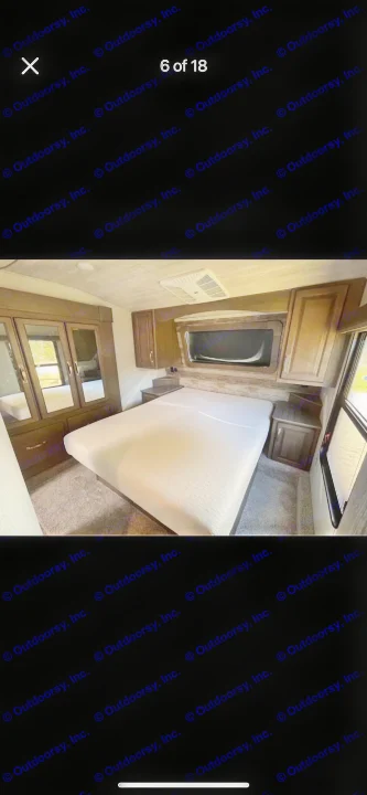 Spacious RV rental bedroom featuring a queen bed, mirrored wardrobe, overhead cabinets, and AC unit for comfortable travel.. Keystone RV Cougar 2021