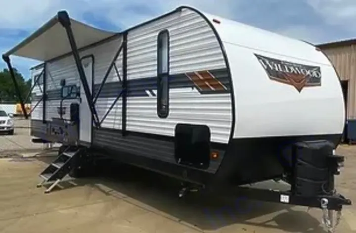 A long white travel trailer RV with an extended awning and stairs, parked for an RV rental. Ready for your next camping trip!. Forest River Wildwood 2021