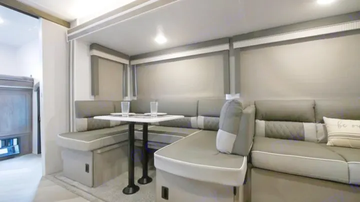 Modern RV rental interior featuring a spacious U-shaped dinette with comfortable gray seating.. Forest River Wildwood 2021