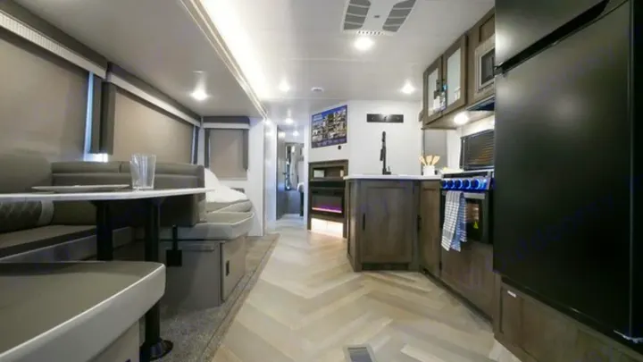 Bright RV rental interior features modern kitchen, dinette, and fireplace, perfect for your next adventure.. Forest River Wildwood 2021