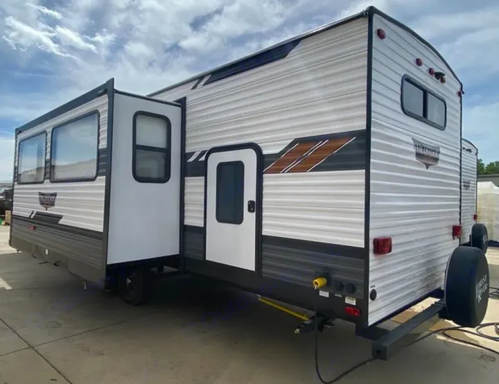 White & gray travel trailer RV rental with extended slide-out for spacious outdoor living.. Forest River Wildwood 2021
