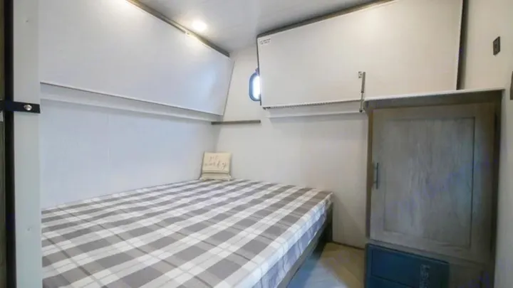 Inside an RV rental, a comfy bedroom features a plaid bed, fold-down bunks, and a cabinet. Great for family trips.. Forest River Wildwood 2021
