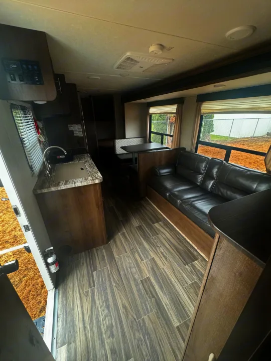RV rental interior: functional kitchen, cozy dinette, and sofa. Wood-look floors, bright windows offer comfortable travel.. Shasta 26db 2020