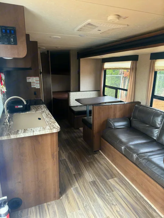 Modern RV rental interior: kitchen, dinette, sofa, and bunk beds. A spacious and clean living space for travel.. Shasta 26db 2020