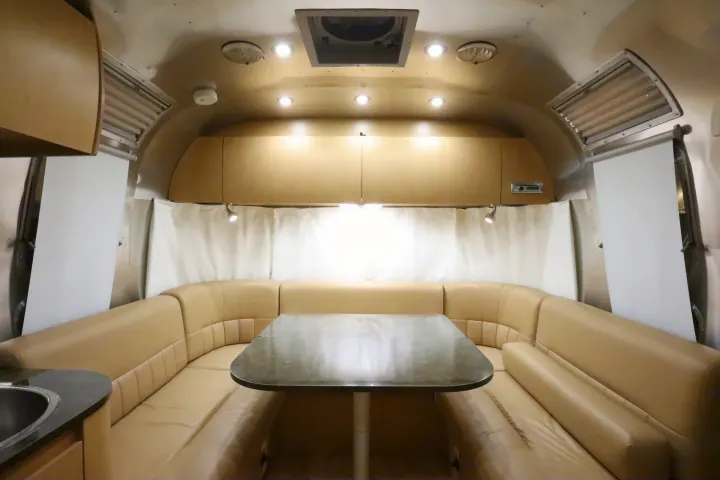 Spacious RV rental interior with a cozy U-shaped dining area, complete with a table, comfortable seating, and overhead cabinets.. Airstream Flying Cloud 2016