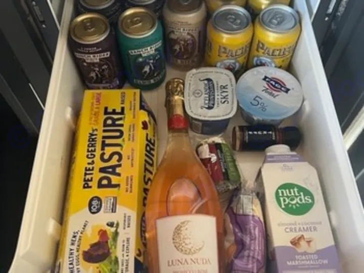 This well-stocked fridge inside an RV rental is packed with drinks, eggs, yogurt, and snacks, ready for a road trip adventure.. Ford Transit 2023