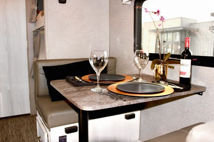 Cozy rv rental dining area, set for two with wine, plates, & an orchid. Perfect for a relaxing meal on the road.. Forest River Rockwood GeoPro 2019