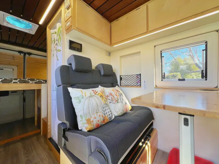 Explore this RV rental's spacious interior: dining table, sofa seating with fall pillows, overhead cabinets, and bed.. Ram promaster 2500 2017