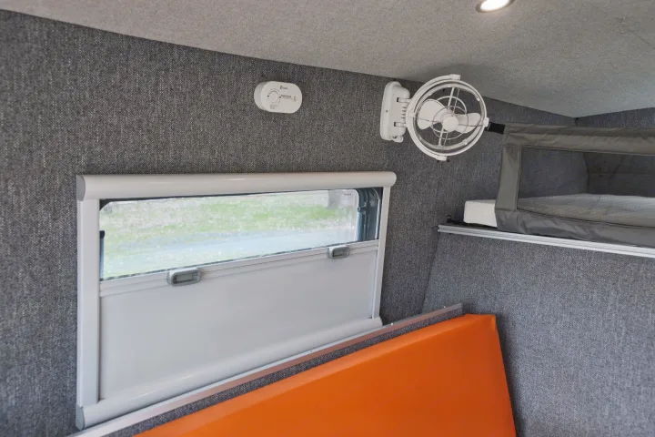 RV rental interior featuring a window, carbon monoxide detector, mounted fan, and bunk bed with grey fabric walls.. Gmc sierra 1500 2024