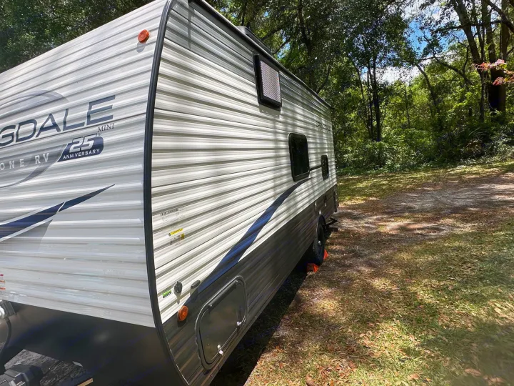 RV rental parked at a serene campsite, surrounded by trees.. Keystone RV Springdale 2024