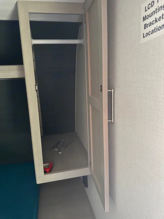RV rental compact closet with a hanging rod and storage shelf, designed for efficient use of space.. Keystone RV Springdale 2024