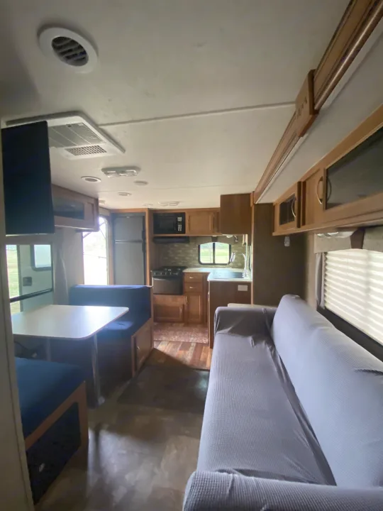 View inside a comfortable RV rental: dinette, full kitchen (stove, microwave, sink, fridge), and sofa for travelers.. Coachmen Apex 2014