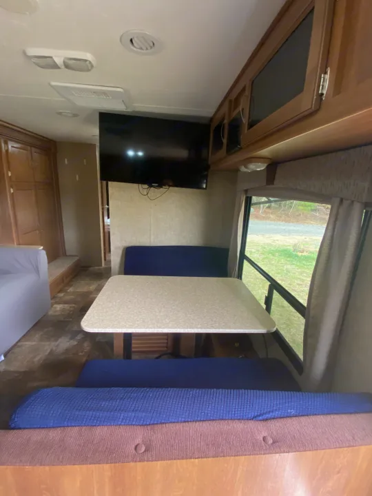Cozy RV rental interior featuring a dinette, wall-mounted TV, and large window views.. Coachmen Apex 2014